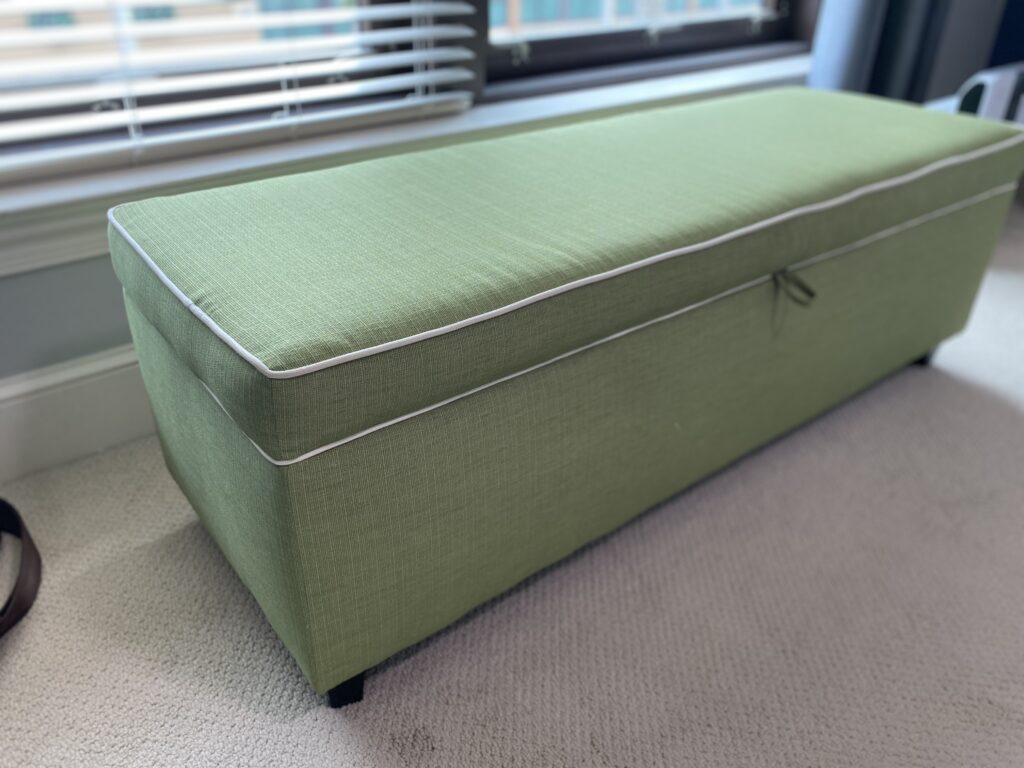 Before upholstery process, old, green bench with storage.